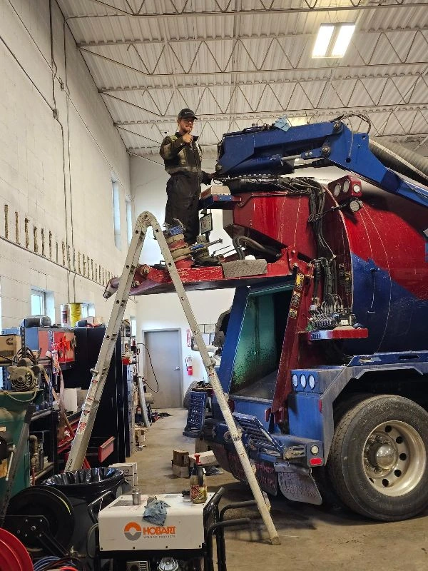 Technician performing hydrovac truck repairs